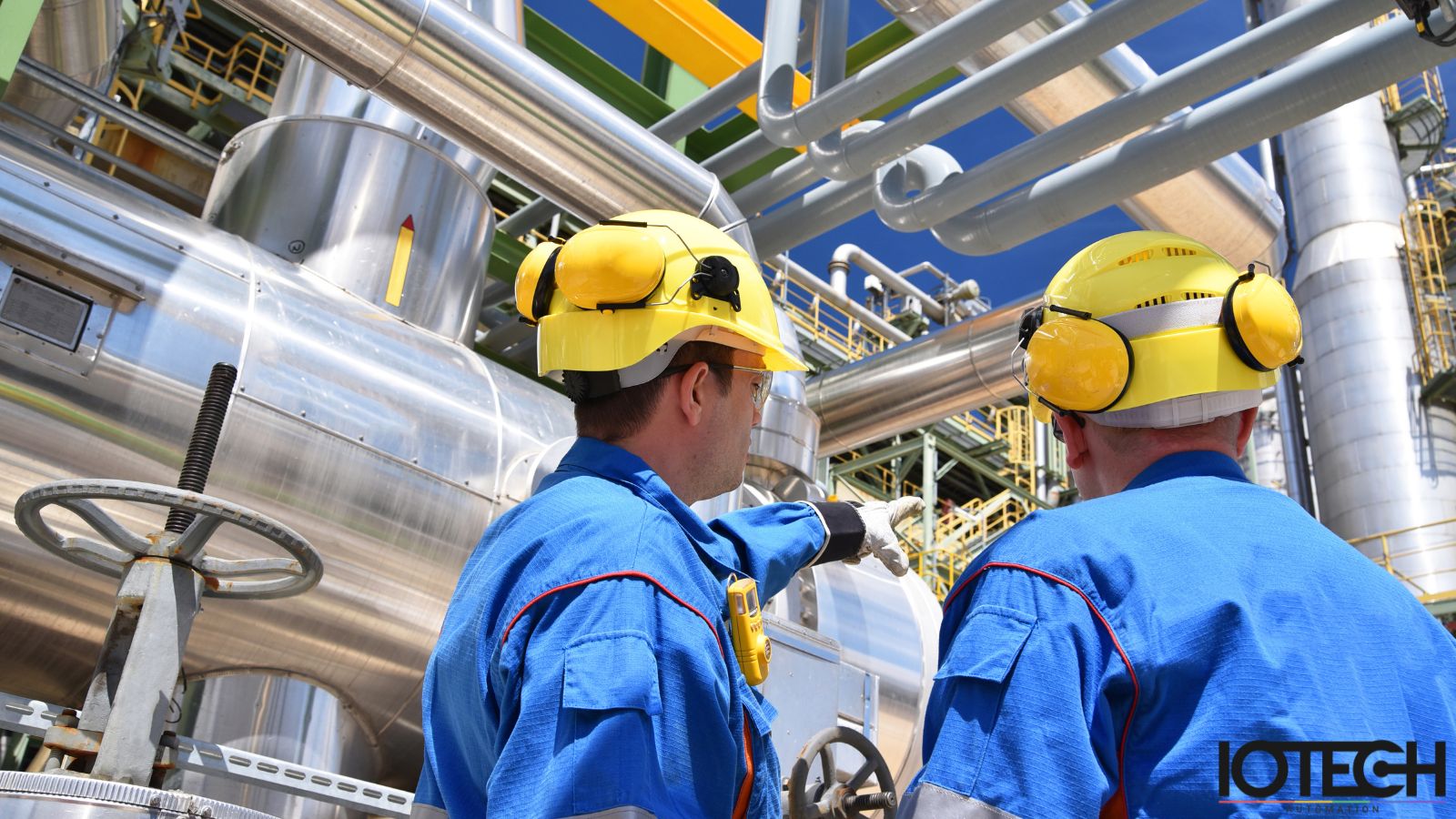 IOTECH engineers in blue work suits at an industrial process plant